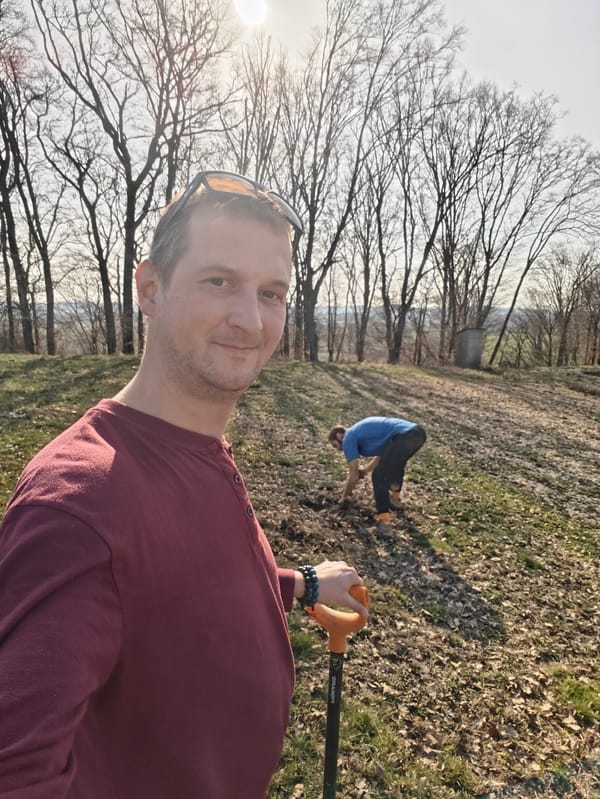 Jakub s rýčem při sázení stromů ve Slovinsku, v pozadí Roger sází stromek.